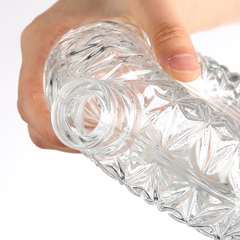 Botella de vidrio redonda con patrón intrincado.