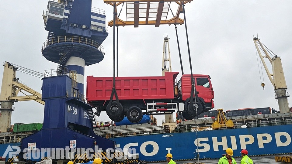 Camiones volquete SINOTRUK HOWO TX 6x4 bicolor atracados en el puerto para envío marítimo a la República del Congo